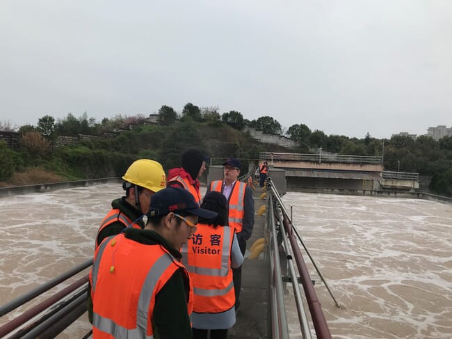 People standing over fermentation basins at a water treatment plant
